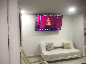 a room with a couch and a tv on the wall at Hostal Jerry Inn in Valledupar