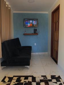 een woonkamer met een zwarte bank en een tv bij Casa Ferradurinha & Geribá in Búzios