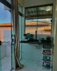 een keuken met een wastafel en een glazen raam bij Casa Ferradurinha & Geribá in Búzios