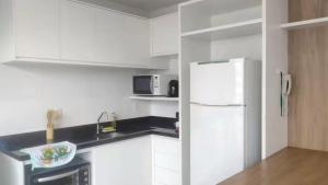 a kitchen with white cabinets and a white refrigerator at Ed Highline, piscina, lavanderia in Joinville