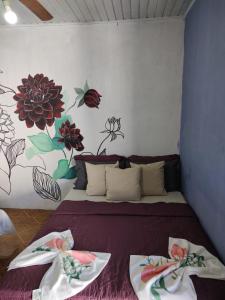 a bed in a room with flowers on the wall at Pousada Villa da Música Beira Mar Dàlia Pontal Centro in Paraty