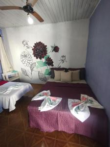 two beds in a room with flowers on the wall at Pousada Villa da Música Beira Mar Dàlia Pontal Centro in Paraty
