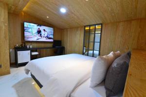 1 dormitorio con 1 cama grande y TV en la pared en K Boutique Hotel, en Yeosu