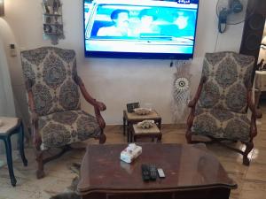 a living room with two chairs and a flat screen tv at Quiet Living in Cairo
