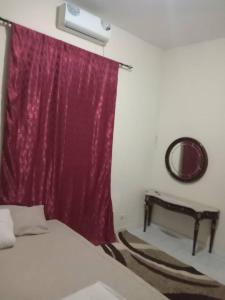 a bedroom with a bed and a red curtain at CHEZ Mamadou et Binetou in Mbour