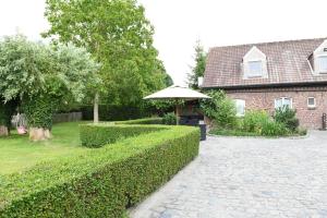 a garden with an umbrella and a brick house at Vakantiewoning Nijkenhof in Ninove