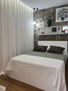 ein Schlafzimmer mit einem weißen Bett und einer Wand in der Unterkunft Sequeira Arantes Casa 1 in Terras de Bouro + 16 Fotos