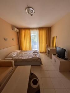 RogachevoにあるHarmony Hills Tomovi Apartament F43のベッドとテレビのある寝室 +4枚の写真