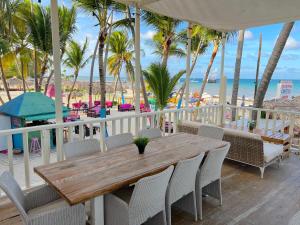 蓬塔卡纳DUCASSI DELUXE playa LOS CORALES - rooftop pool, restaurants and beach club的海滩阳台的木桌和椅子