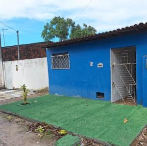 a blue building with a door and a grass yard at Casa em Parnamirim próximo ao centro in Parnamirim