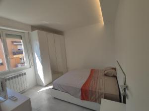 a white bedroom with a bed and a window at Appartamento Helena Duomo in Pisa