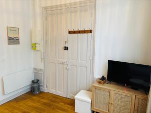 a living room with a television and a white door at Cozy studio en centre ville in Beauvais +3 photos