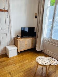 a living room with a tv and a table and a stool at Cozy studio en centre ville in Beauvais