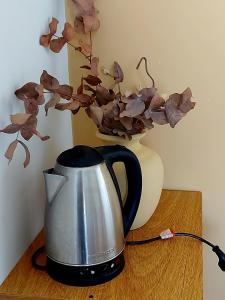 a coffee pot on a table with a vase with flowers at Departamento Cerca Parque Termal Rodo-Hue 2 in Dolores