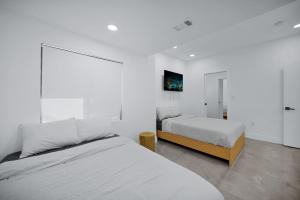 deux lits dans une chambre aux murs blancs dans l'établissement Lux Modern 4BR Villa with Pool in Miami, à Miami 52 autres photos