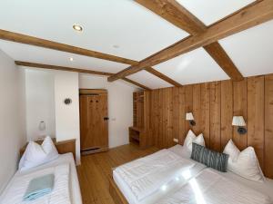 two beds in a room with wooden walls and beams at Carmaliva in Innerkrems