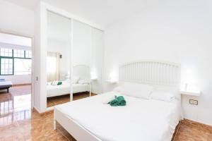 a white bedroom with a white bed and a mirror at Live Arico Lapa cerca de la playa in Arico