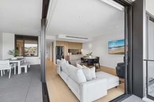 ein Wohnzimmer mit weißen Sofas und eine Küche in der Unterkunft Solea in Avoca Beach