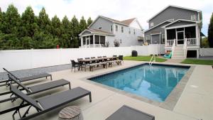 Un patio trasero con piscina, mesa y sillas. en Coastal Sanctuary, en West Cape May