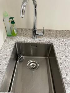 a stainless steel kitchen sink with a faucet at tranquil cosy bush cabin in Lower Hutt +46 photos