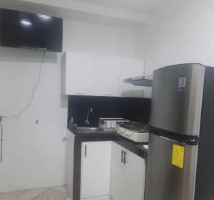 a small kitchen with a refrigerator and white cabinets at MiniSuite in Machala