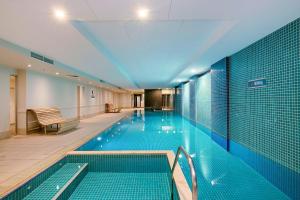 a swimming pool in a building with blue tiles at Belle Escapes - Oceanfront Luxe at The Pier in Glenelg