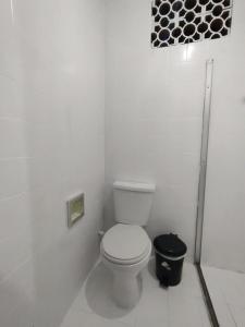 a white bathroom with a toilet and a trash can at Pousada Villa da Música Beira Mar Dàlia Pontal Centro in Paraty