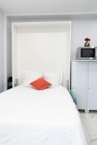 a bedroom with a white bed with a microwave on it at Appartement cosy A Paris RER B in Gentilly