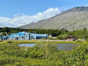a large blue building with a mountain in the background at Hotel Breiddalsvik in Breiðdalsvík