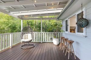 eine Veranda mit einem Schaukelstuhl auf einer Terrasse in der Unterkunft Cottage on Riv - Winter Holiday Mid-Week Special in Terrigal