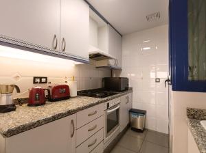 a kitchen with white cabinets and a counter top at Valencia Playa Patacona Resort in Valencia +29 photos