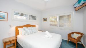 扬巴Avalon 2的一间卧室，里面有一张床、一把椅子和两扇窗户