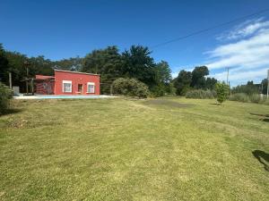 a red house in a field with a yard at La Colorada Dolores in Dolores