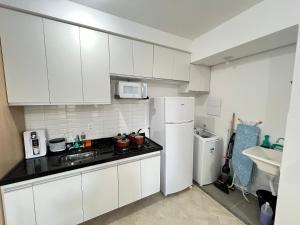 a kitchen with white cabinets and a white refrigerator at LK Centro 9 in Belo Horizonte +19 photos