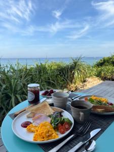 a table with plates of food on a table with the ocean at ViLLA SHiNAHA ヴィラシナハ 与論島 in Yoron