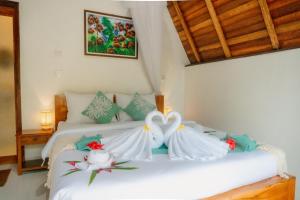 two swans are sitting on a bed in a room at Kacu Bali Munduk in Munduk