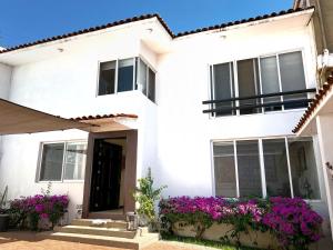 ein weißes Haus mit lila Blumen davor in der Unterkunft Casa YOKO in Oaxaca de Juárez