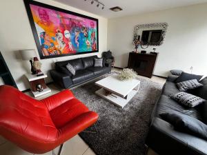 ein Wohnzimmer mit einem schwarzen Sofa und einem roten Stuhl in der Unterkunft Casa YOKO in Oaxaca de Juárez