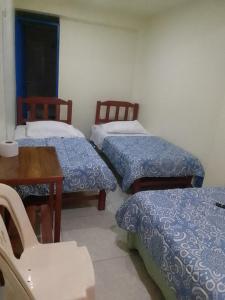 a room with three beds and a table and a table and chairs at Hospedaje TUTUMEME in Churín +28 photos