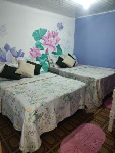 two beds in a room with flowers painted on the wall at Pousada Villa Da Música Beira Mar Lótus Pontal Centro in Paraty