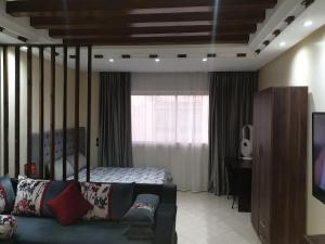 a bedroom with a bed and a couch and a television at Superb studio at the ocean in Rabat