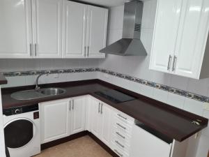 a kitchen with white cabinets and a sink and a microwave at Apartamento Turístico Céntrico Galper in Melilla