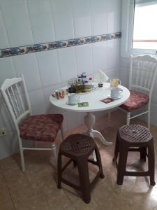 a white table with two chairs and a table with cups andodanxesmoilmoil at Apartamento Turístico Céntrico Galper in Melilla