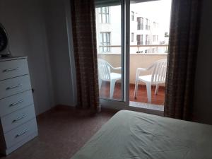a bedroom with a bed and a balcony with two chairs at Apartamento Turístico Céntrico Galper in Melilla +3 photos