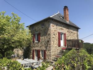 an old stone house with red windows and a balcony at Maison confortable avec animaux acceptés et jardin clos - FR-1-489-552 in Ferrières-sur-Sichon
