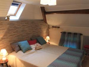 a bed in a bedroom with a brick wall at Maison confortable avec animaux acceptés et jardin clos - FR-1-489-552 in Ferrières-sur-Sichon