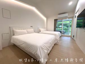 Dos camas en una habitación con paredes blancas. en 夢幻城堡民宿, en Wujie