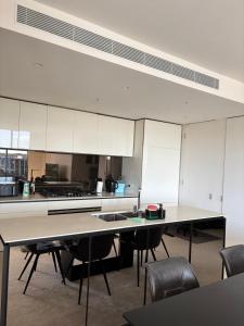 una cucina con armadi bianchi, tavoli e sedie di 5 star residence Room with Ensuite for rent in Benowa a Gold Coast