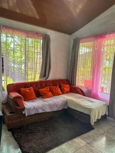a couch with orange pillows in a room with windows at Tortuguero Family House in Colorado