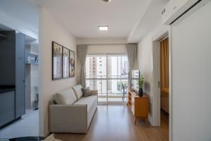a living room with a couch and a large window at CONFORTO JH PALHANO, Ap 1507 in Londrina